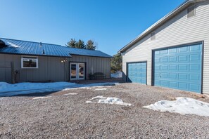 Il s’agit d’une propriété résidentielle dotée d’une allée en gravier, d’un garage avec une porte bleue et d’un toit en métal.