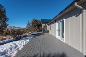 A wooden deck leading to a building with a dark roof and a clear sky. - Mountain Views of the San Juans. Great outdoor living, near bike, hike and swim. (Ridgway)