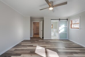 A hallway with a wooden herringbone floor, a ceiling fan, and a sliding glass door leading to a bathroom. - Mountain Views of the San Juans. Great outdoor living, near bike, hike and swim. (Ridgway)