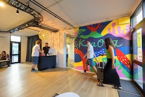 A modern interior with a colorful wall mural, a wooden floor, and a staircase. - Urban Lounge Sleeepery Dorm (Rotorua)