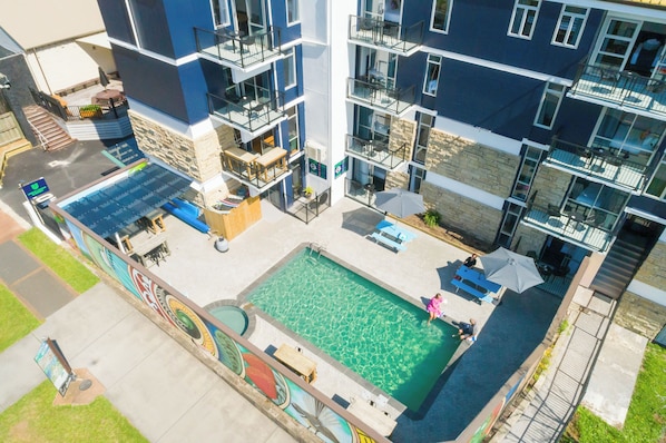 A multi-story building with a rooftop pool area, outdoor seating, and a mural. - Urban Lounge Sleeepery Dorm (Rotorua)