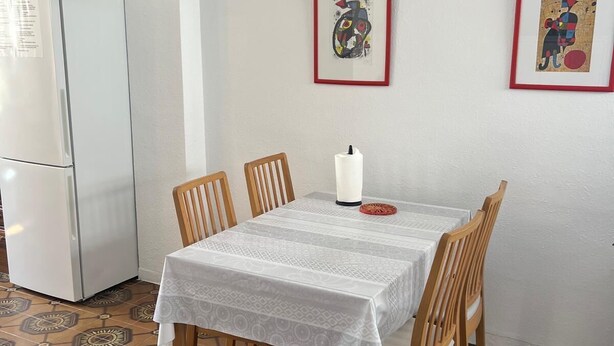 Ein Essbereich mit einem Tisch für vier Personen, umgeben von Holzkästen, einer weißen Tischdecke und einer hängenden Pendelleuchte.