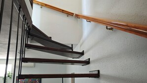 Eine Treppe mit hölzernen Geländern und Metallstreben, die zu einer Zwischenebene mit einem gerahmten Bild führt.