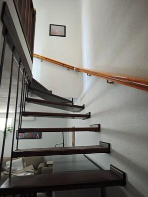 A staircase with wooden handrails and metal supports, leading to a landing with a framed picture. - Two-story house in P. Andaluz/Torróx Costa. 3 bedrooms, sleeps 5, and community pool (Torróx Costa)