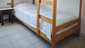 Ein Stockbett mit Schreibtisch und Lampe in einem Zimmer mit Fliesenboden.