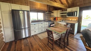 A kitchen with wooden cabinets, a stainless steel refrigerator, a microwave, and a dining table with chairs.
