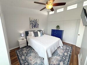 A bedroom with a bed, nightstands, a dresser, a ceiling fan, and a wall-mounted TV. - Beach Breeze - Across from Beach (Panama City)