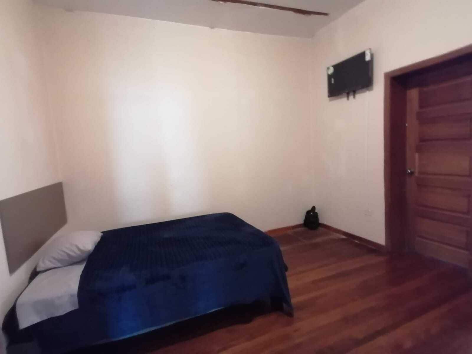 Une chambre à coucher avec un lit, une porte en bois et un climatiseur fixé au mur.
