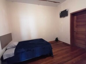 Une chambre à coucher avec un lit, une porte en bois et un climatiseur fixé au mur.