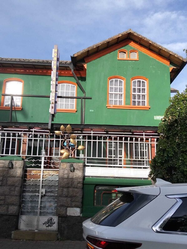 Un bâtiment écologique aux fenêtres dotées de cadres orange, une porte en métal et un escalier menant à l’entrée.