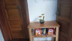 Una mesa de madera con un estante que sostiene bolsas de aperitivos y una pequeña planta en maceta.