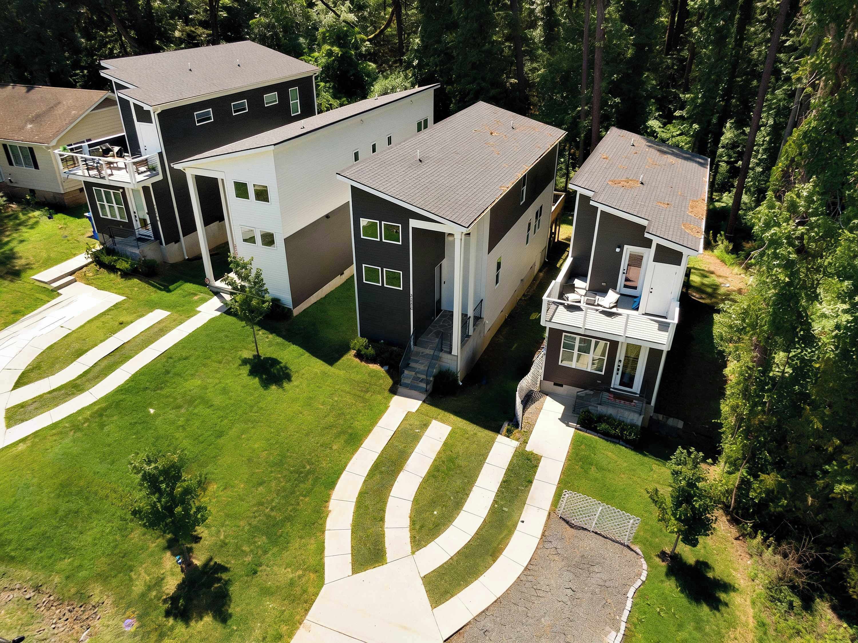 A residential area with modern two-story houses, a well-maintained lawn, and a clear driveway.