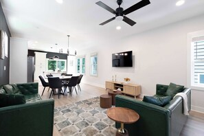 Un salon moderne avec des canapés verts, une table basse en bois et un ventilateur de plafond.