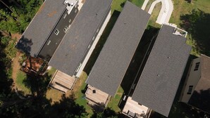 Zona residencial com várias casas independentes, cada uma com sua entrada de garagem e um pequeno jardim frontal.