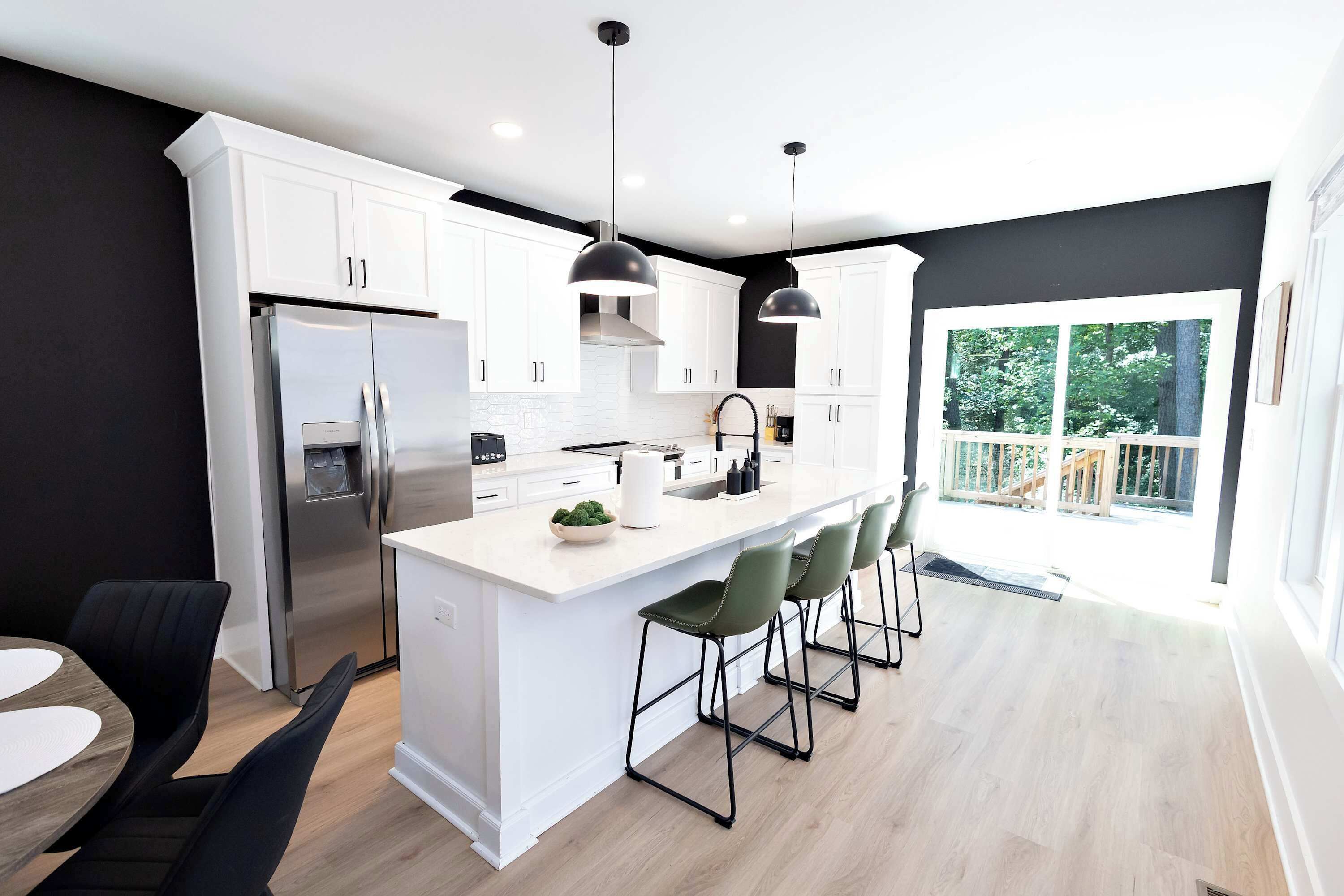 A modern kitchen with a central island, stainless steel appliances, and a large window overlooking a deck.