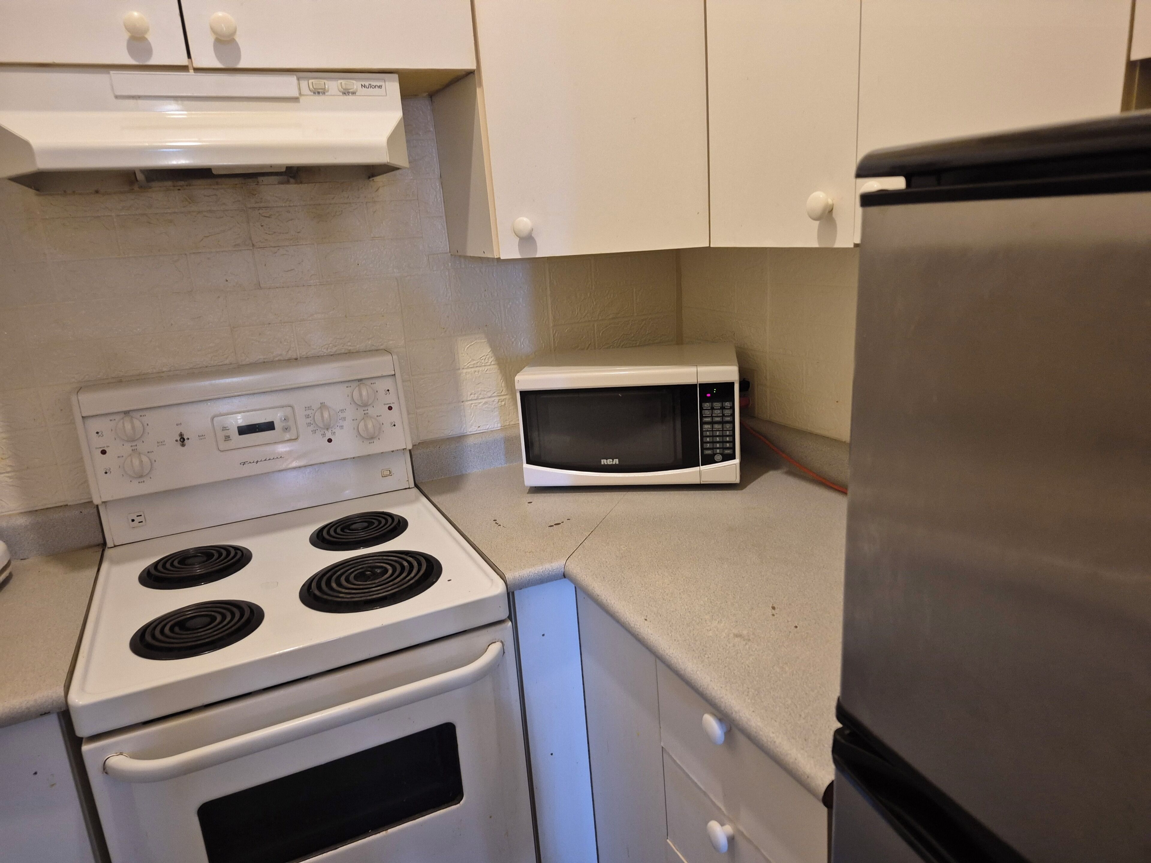 A kitchen with a white stove, a microwave, and a refrigerator.