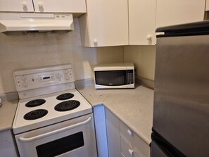 A kitchen with a white stove, a microwave, and a refrigerator.