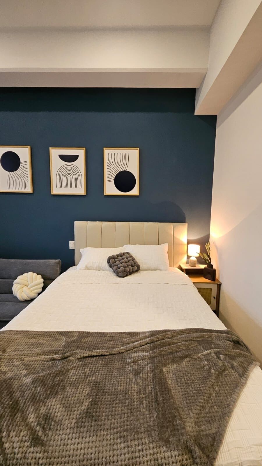 A bedroom with a bed, a nightstand, and three wall art pieces.