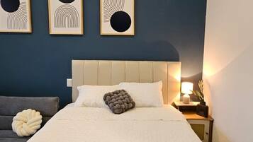 A bedroom with a bed, a nightstand, and three wall art pieces.