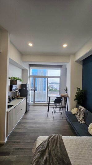 Um apartamento moderno com cozinha compacta, área de refeições e varanda com vista para a cidade.