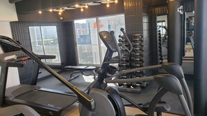 Un gimnasio con equipo de ejercicios, cinta de correr y banco para pesas.