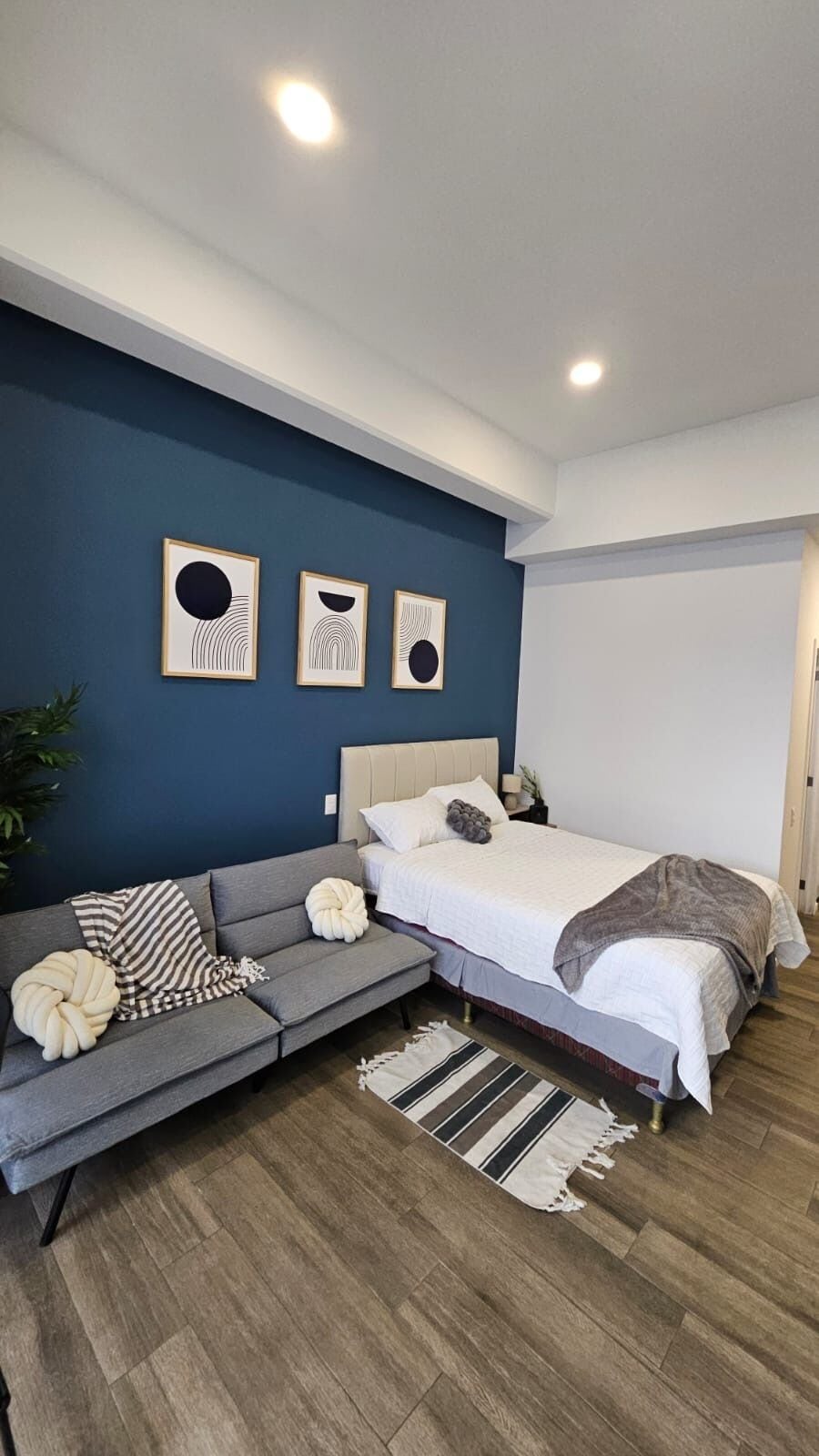 A modern bedroom with a bed, a sofa, and a small side table.