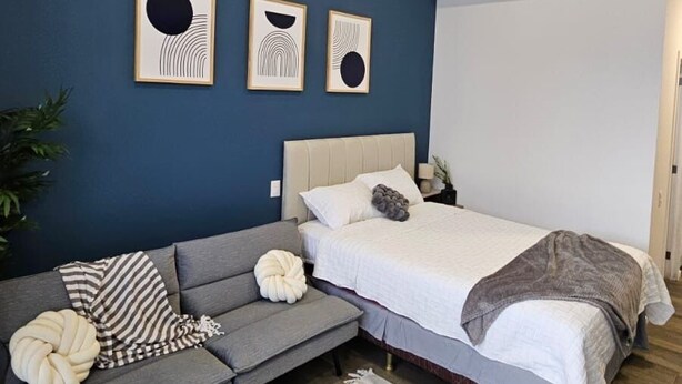 Un dormitorio moderno con cama, sofá y una mesita auxiliar.