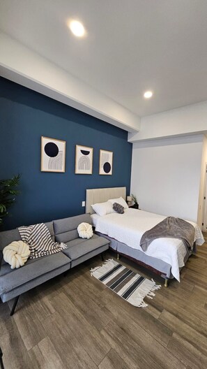 Une chambre à coucher moderne avec un lit, un canapé et une petite table d’appoint.