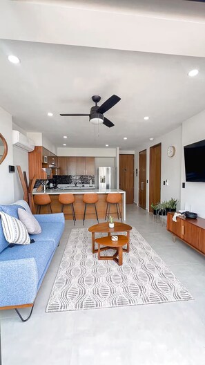 A modern living room with a sofa, a coffee table, and a TV. - Serenity Tower 601, 1-Bedroom Apartment with Rooftop Pool and Ocean and Mountain Views (Puerto Vallarta)