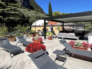 Eine Terrasse im Freien mit Lounge-Möbeln, Grillplatz und Pflanzen in Töpfen.