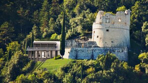 A castle with a modern building adjacent to it. - Apartment with a 150-square-meter Private Terrace and Breathtaking Lake Views (Trentino-Alto Adige)