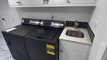 A kitchen with white cabinets, a black stove, and a sink.