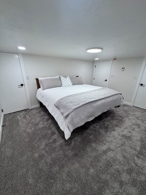 A bedroom with a bed, carpeted floor, white walls, and a ceiling light. - Idaho Falls River Run Retreat, EV charger, 
4-E-bikes, 3-kings, 1-queen, 3-twins (Idaho Falls)