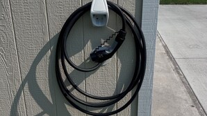 En väggmonterad laddstation med en kabel ansluten till den.