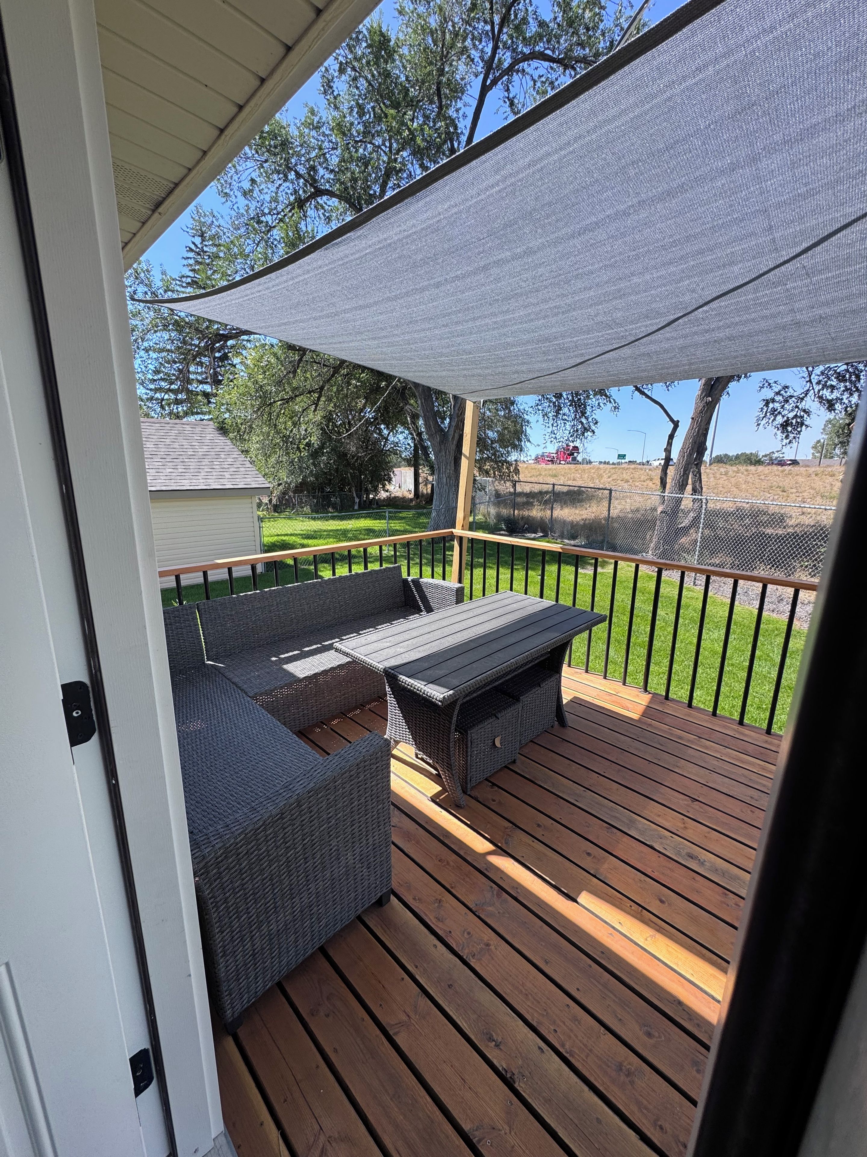 A covered outdoor deck with a built-in seating area and a view of the surrounding landscape.