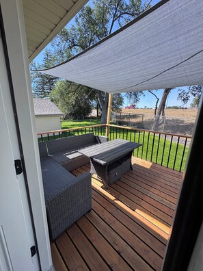 A covered outdoor deck with a built-in seating area and a view of the surrounding landscape. - Idaho Falls River Run Retreat, EV charger, 
4-E-bikes, 3-kings, 1-queen, 3-twins (Idaho Falls)