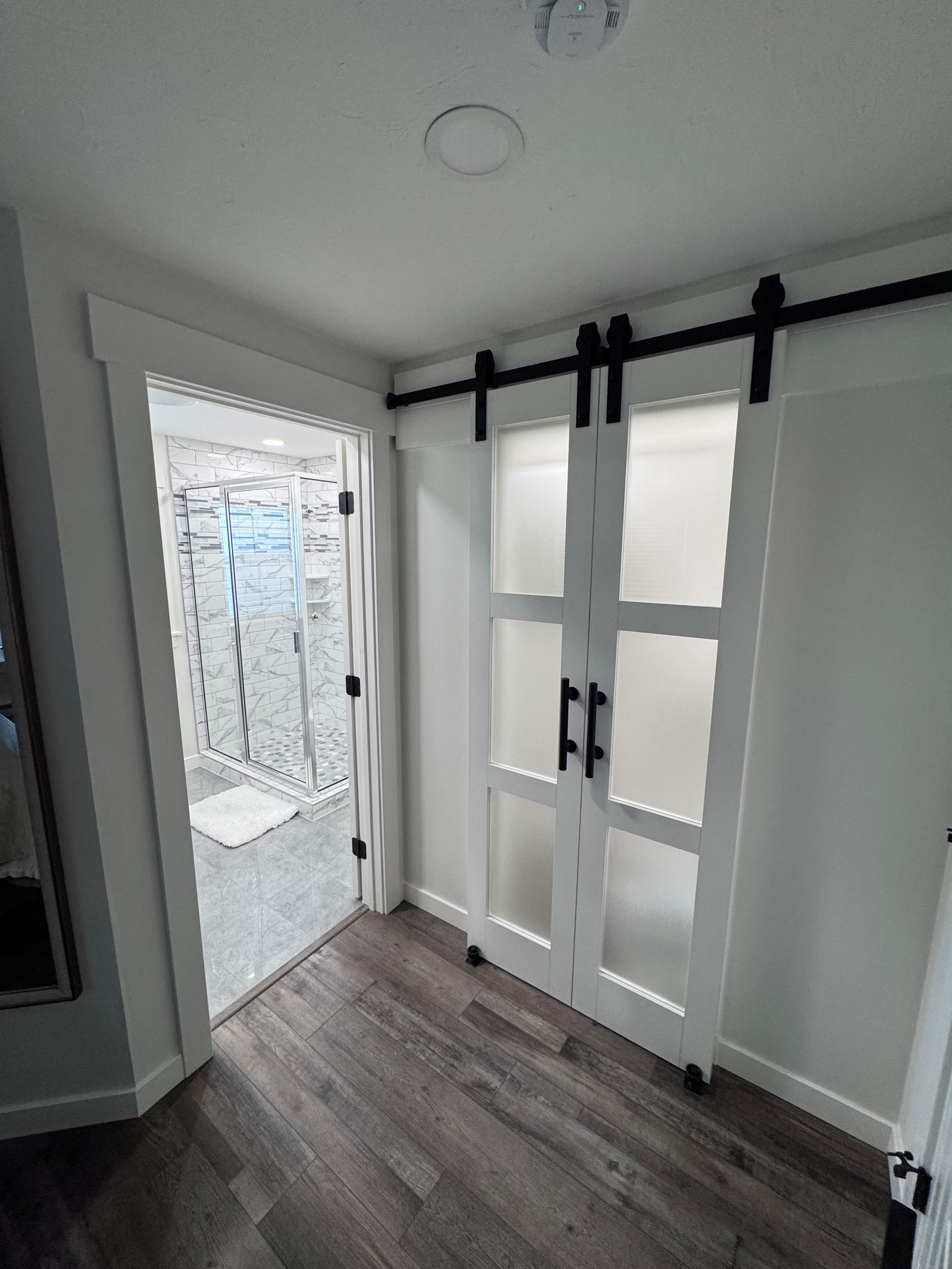 A room with a sliding door leading to a balcony, a wooden floor, and a ceiling with a light fixture.