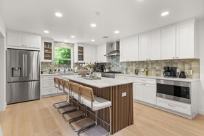 Una cocina moderna con una isla central, electrodomésticos de acero inoxidable y un amplio ventanal.