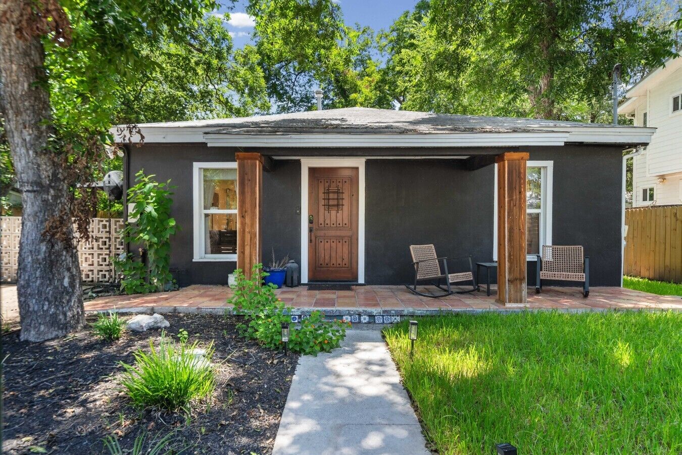 A single-story house with a front porch, a wooden door, and two rocking chairs.