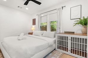 A bedroom with a bed, a bedside table with a lamp, a window with curtains, and a cabinet with a plant. - Chef`s Kitchen + Fire Pit Patio | E Austin Bungalow Mins to Local Favs & Lady Bird (Austin)