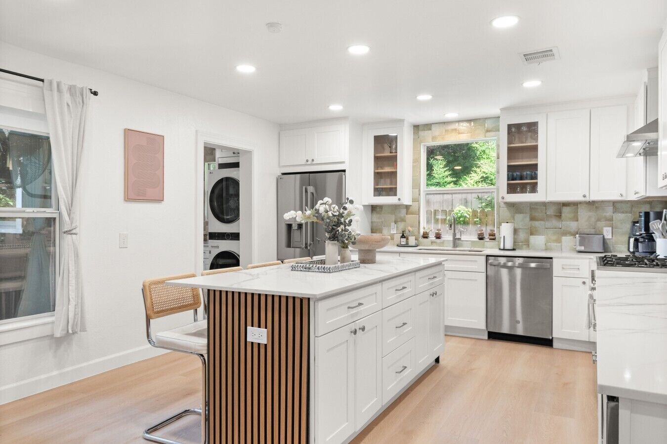 A modern kitchen with white cabinetry, a central island, and a built-in dishwasher.
