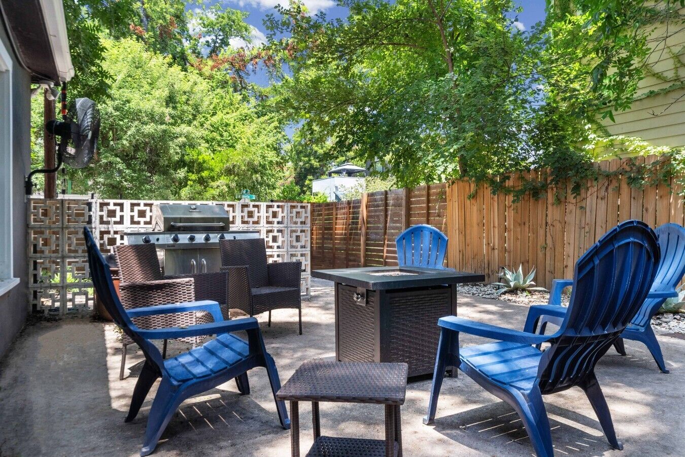 An outdoor patio with a grill, seating, and a view of trees.