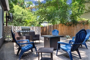 An outdoor patio with a grill, seating, and a view of trees. - Chef`s Kitchen + Fire Pit Patio | E Austin Bungalow Mins to Local Favs & Lady Bird (Austin)