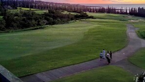 Un campo de golf bajo un cielo despejado y un atardecer.