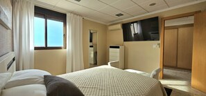 A hotel room with a bed, a chair, a desk, a mirror, a wardrobe, and a window with curtains. - El Marqués Apartment at Dénia Port (Dénia)