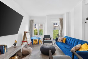 Uma sala de estar moderna com um sofá azul, uma mesa redonda pequena e um cavalete.