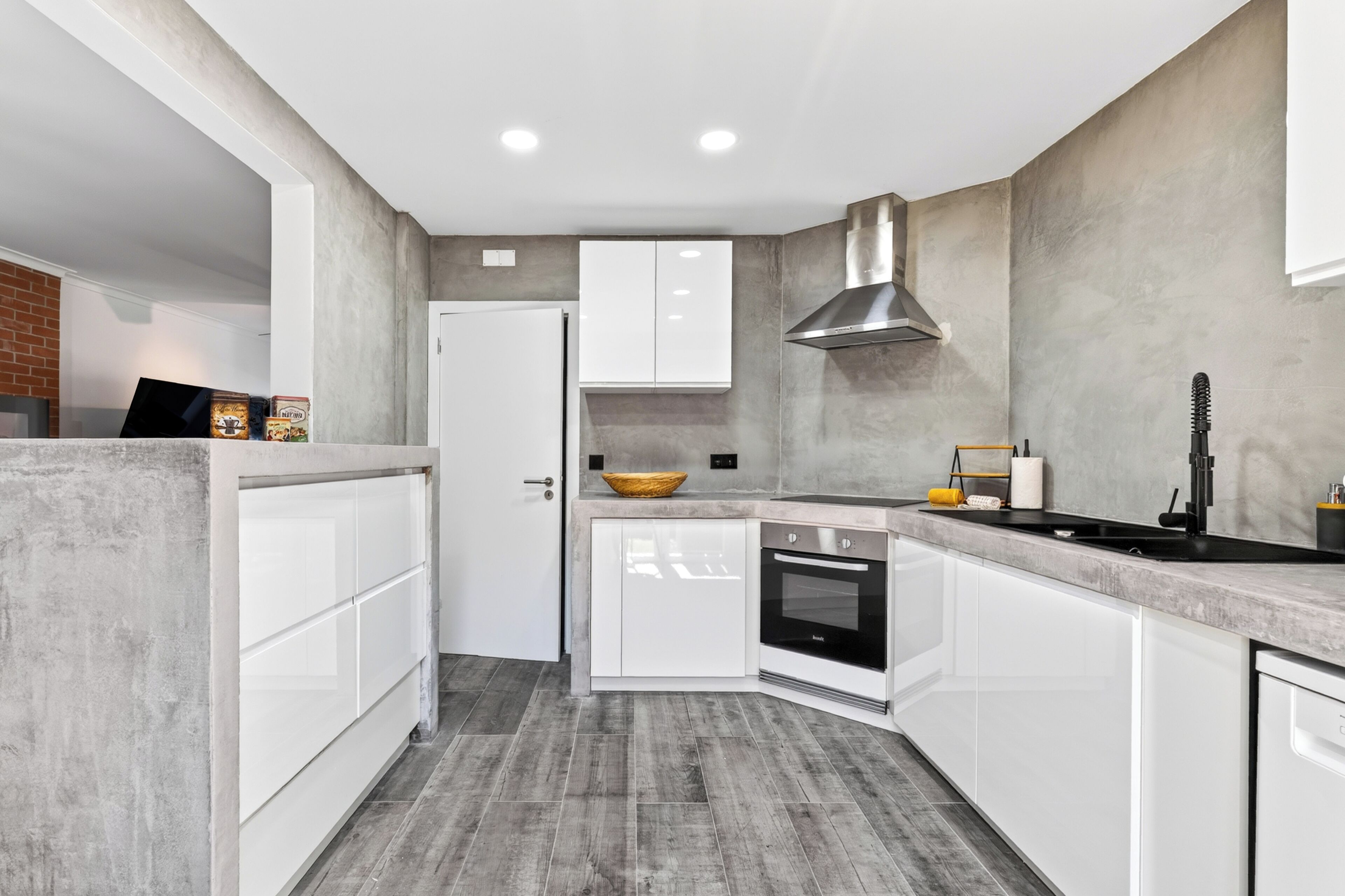 A modern kitchen with white cabinetry, a built-in oven, and a grey backsplash.