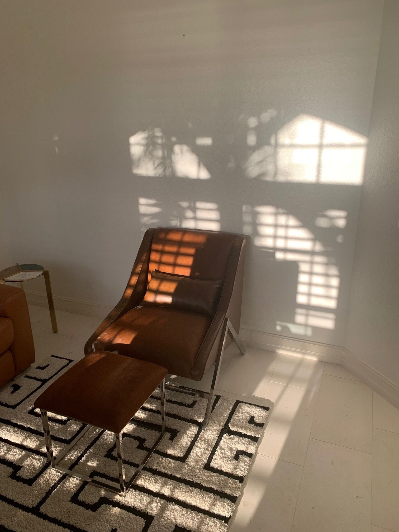Una habitación con una sola silla reclinable, una mesita y una alfombra estampada.