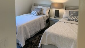 A bedroom with two single beds, a ceiling fan, a nightstand with a lamp, and a painting on the wall. - Island Time Starts Here! 3BR + Den Pool Retreat (Marco Island)