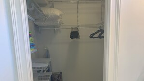 A narrow hallway with storage shelves, a vacuum cleaner, and a rug. - Island Time Starts Here! 3BR + Den Pool Retreat (Marco Island)
